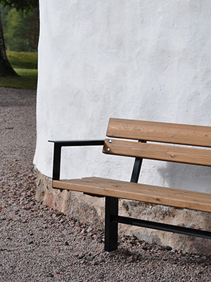 A wooden park bench against a building wall. 